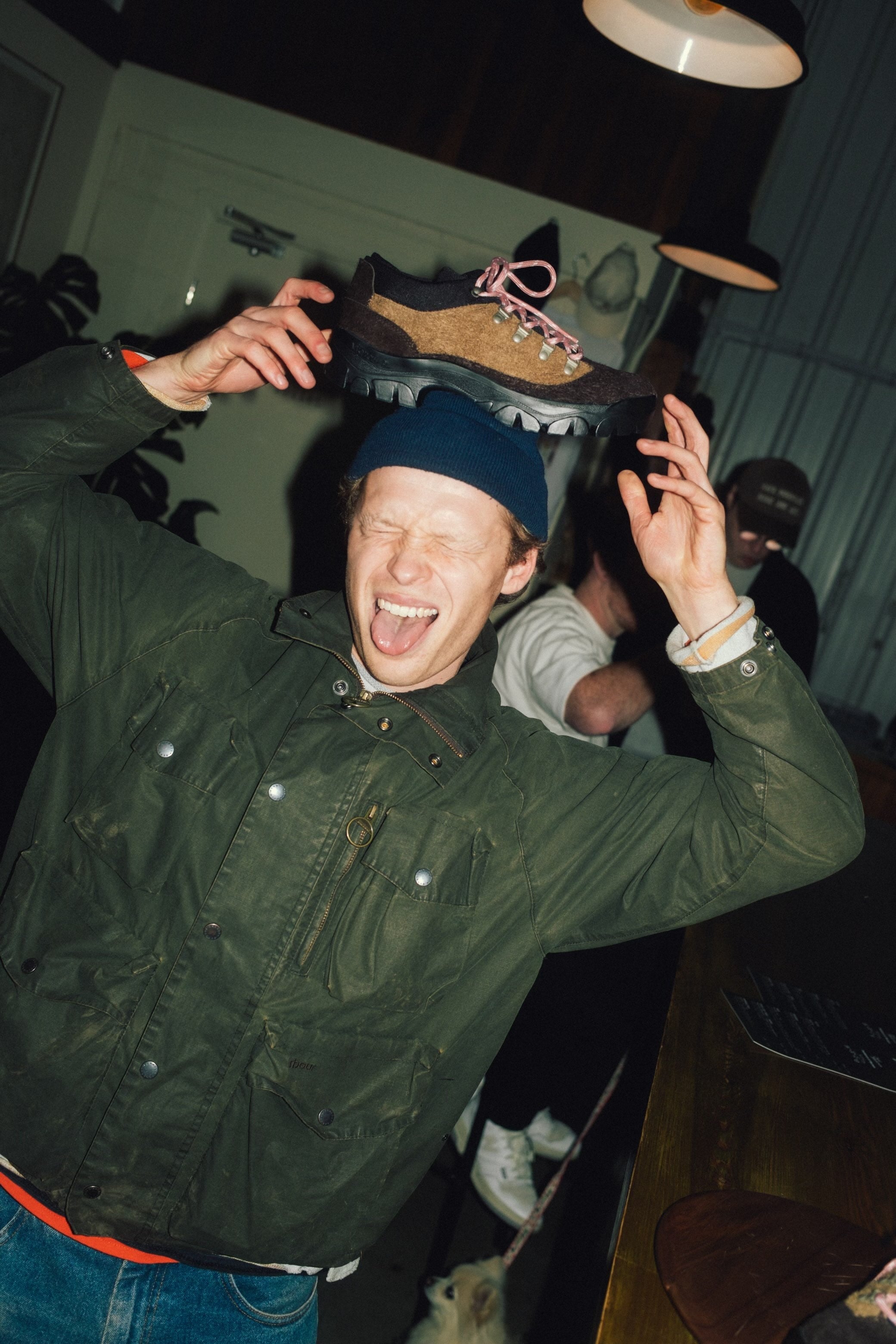 Man in green jacket holding shoe above head