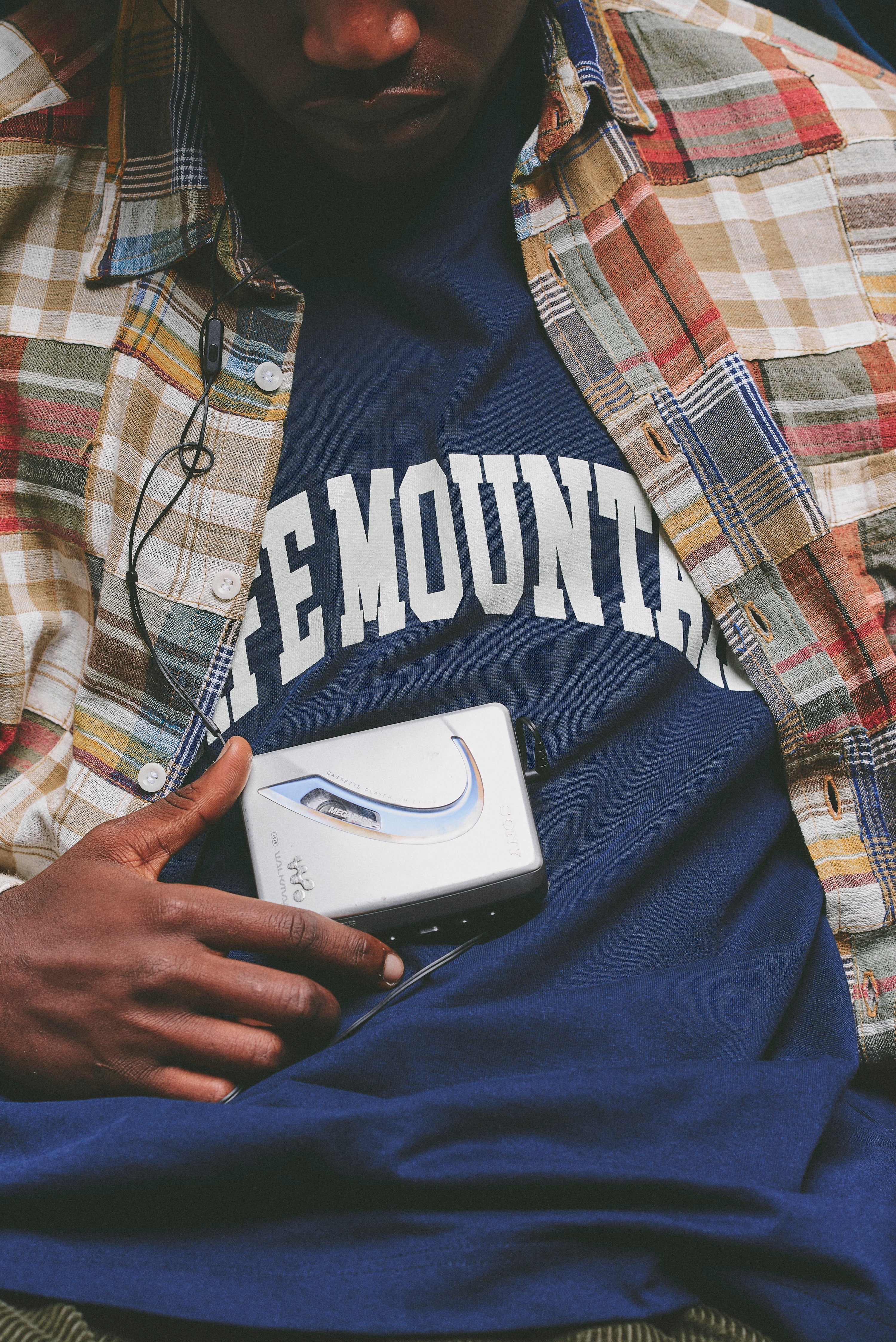 Person wearing a blue t-shirt with 'REMOVABLE' text, holding a small electronic device.